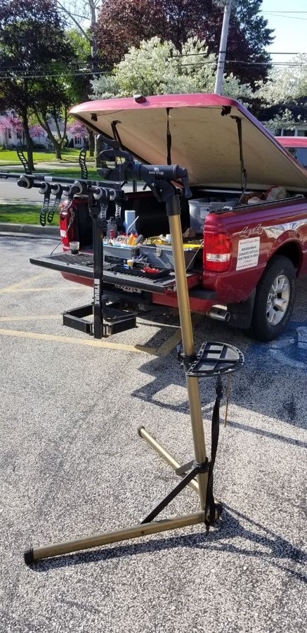 Pickup truck , tailgate open with tools on it, bike repair stand beside it